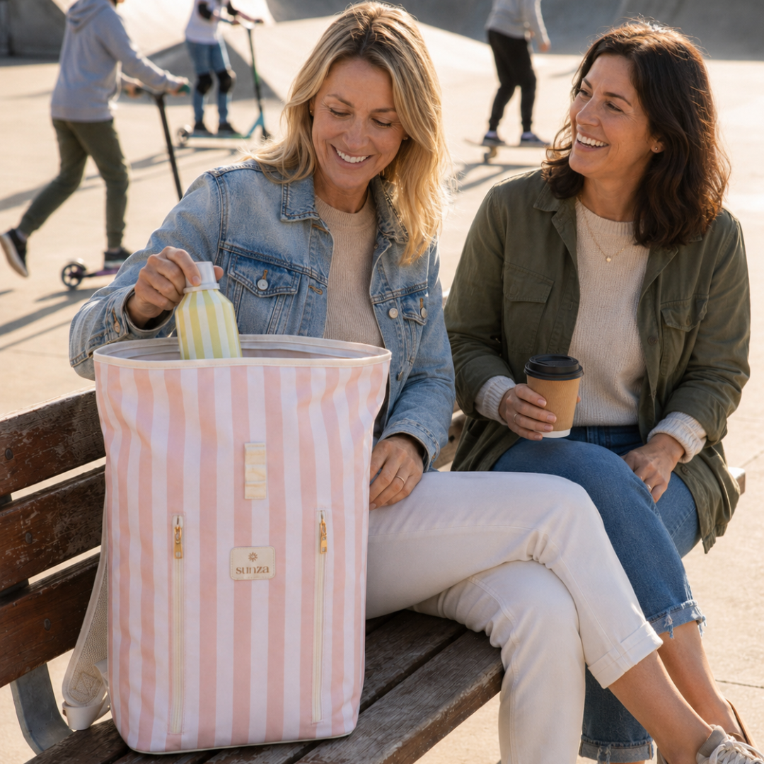 Two women on a bench with Sunza Original Cooler Backpack in Sunset Blush open between them — insulated cooler bag for women Australia