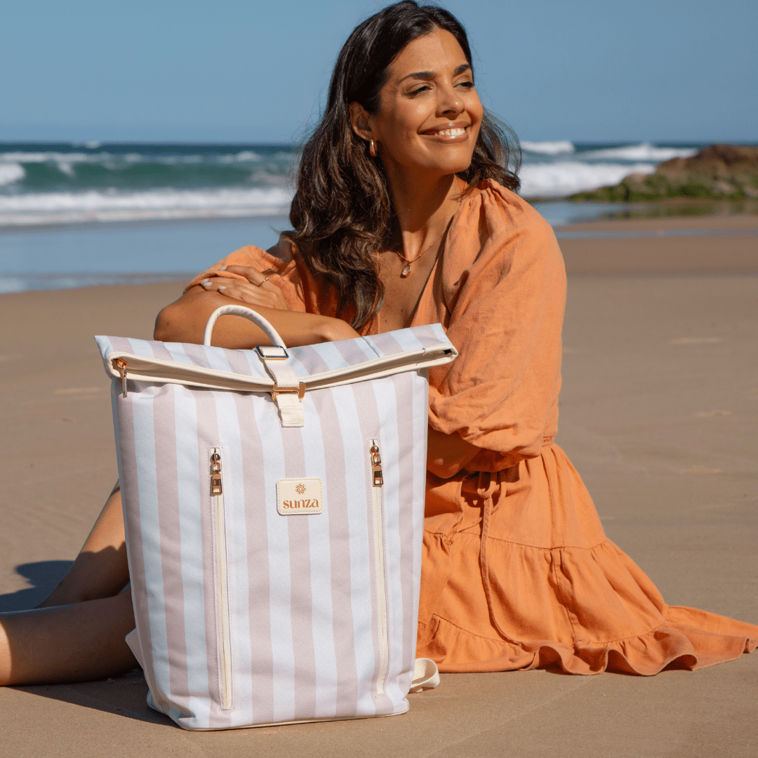 Woman sitting on the beach with Sunza Original Cooler Backpack in Drift Sand — insulated cooler bag for women Australia